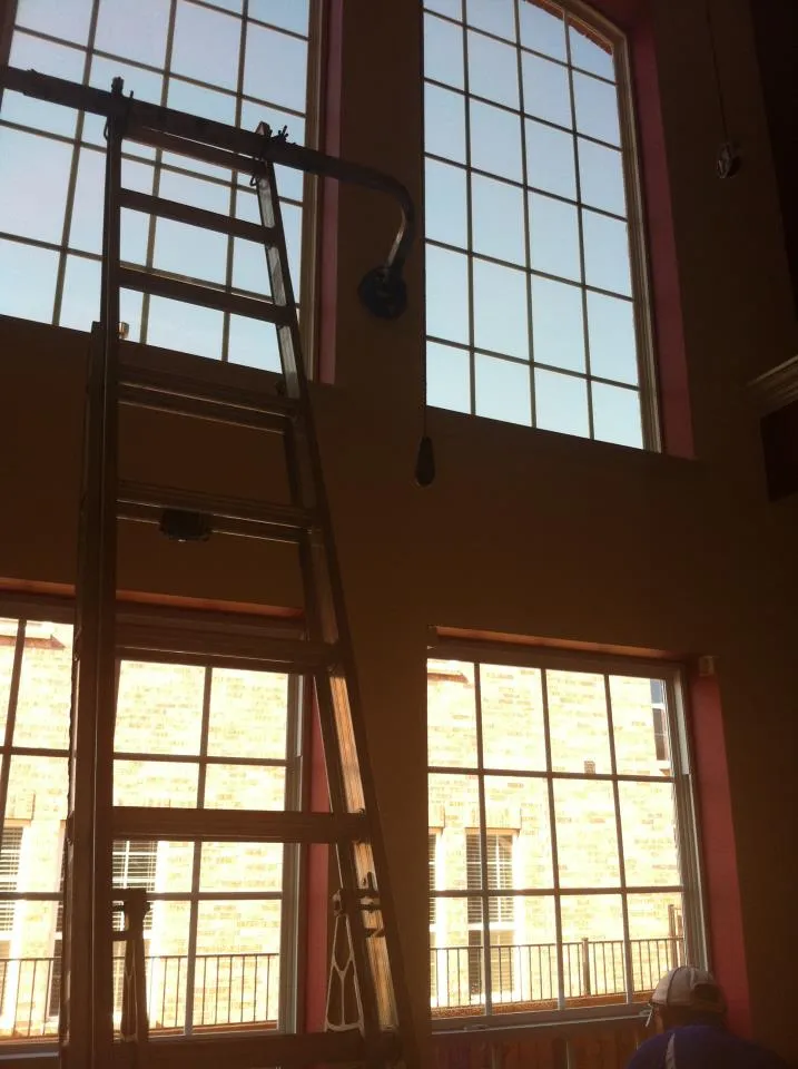 Amertint technician using a ladder for professional high reach window film installation in a Dallas Fort Worth home
